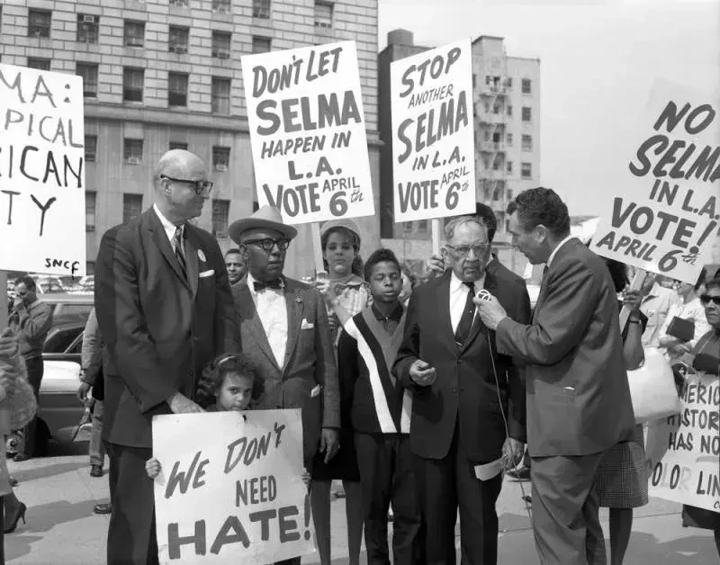 Los Angeles protesters holding signs reading 'Don't Let Selma Happen in L.A. Vote April 6th' and 'We Don't Need Hate'